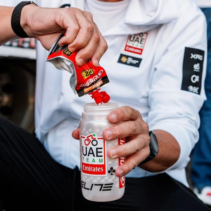 Rider pouring an Enervit C2:1PRO gel into a UAE Team Emirates bottle